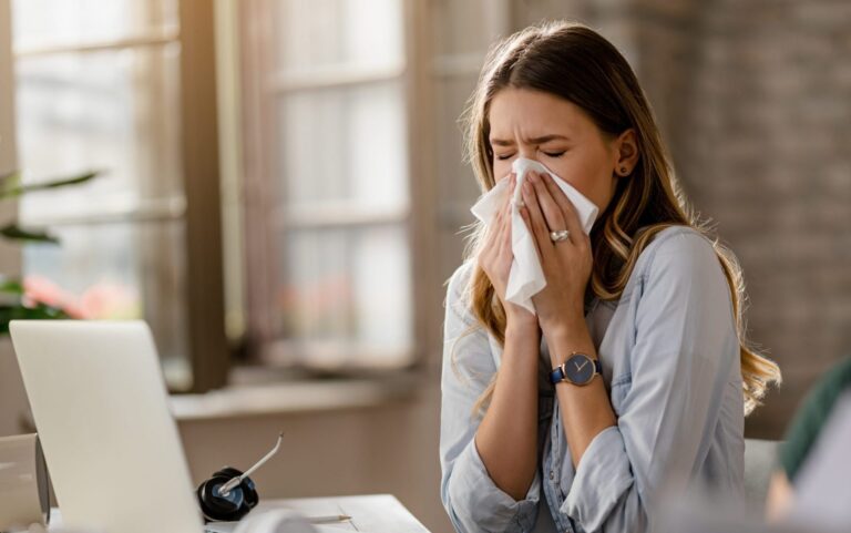 young-sick-businesswoman-sneezing-tissue-while-working-office-scaled-1-e1735931552980